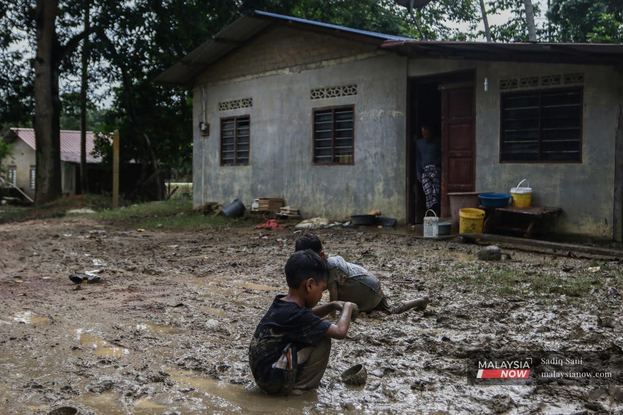 Children play in the mud outside their house in Kampung Pesagi, Pahang, after the floodwaters subside.