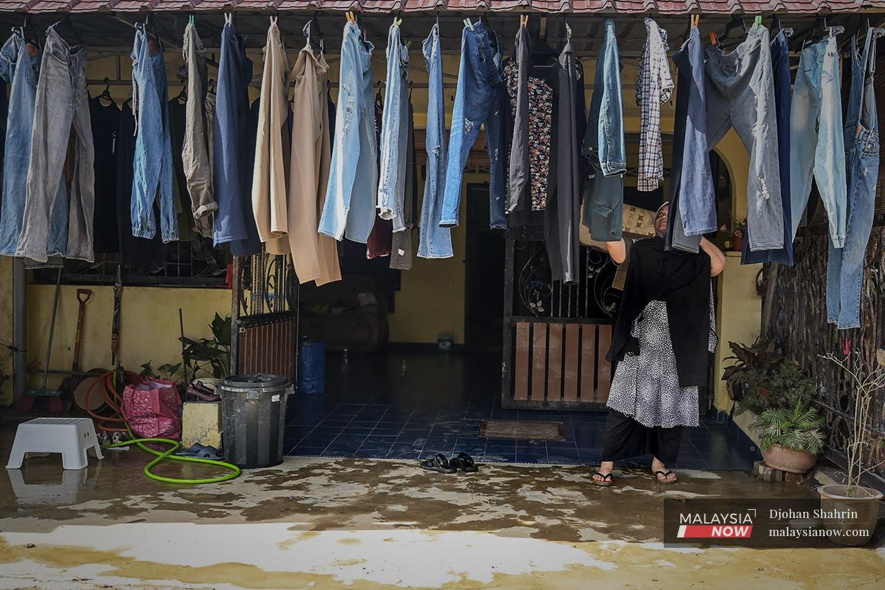 A woman hangs laundry out to dry after returning to her home in Taman Sri Nanding, Selangor.