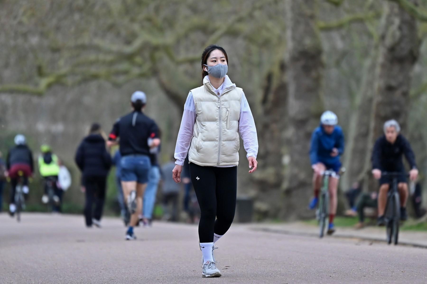 A woman wearing a protective face covering to combat the spread of Covid-19, takes her daily exercise in Battersea Park in London on March 28, 2021. Photo: AFP