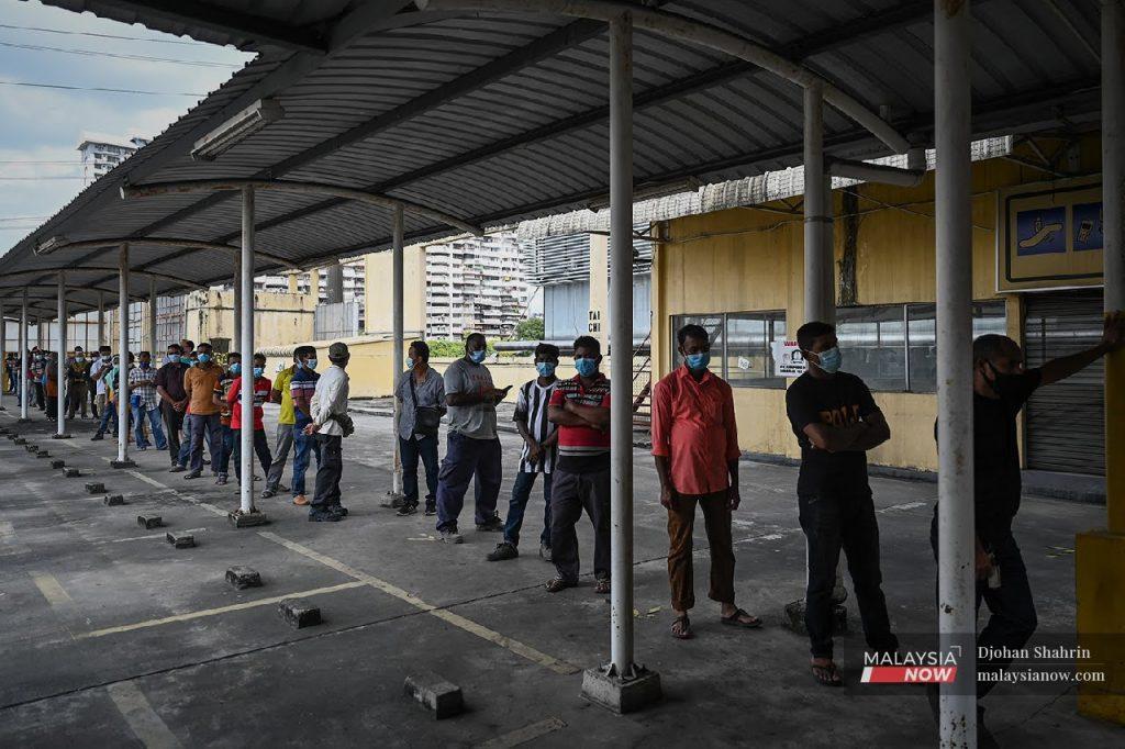 Migrant workers queue in this file picture. Glove maker Supermax has said it will introduce a new foreign worker management policy and enhance its current human resources policies in response to forced labour allegations.