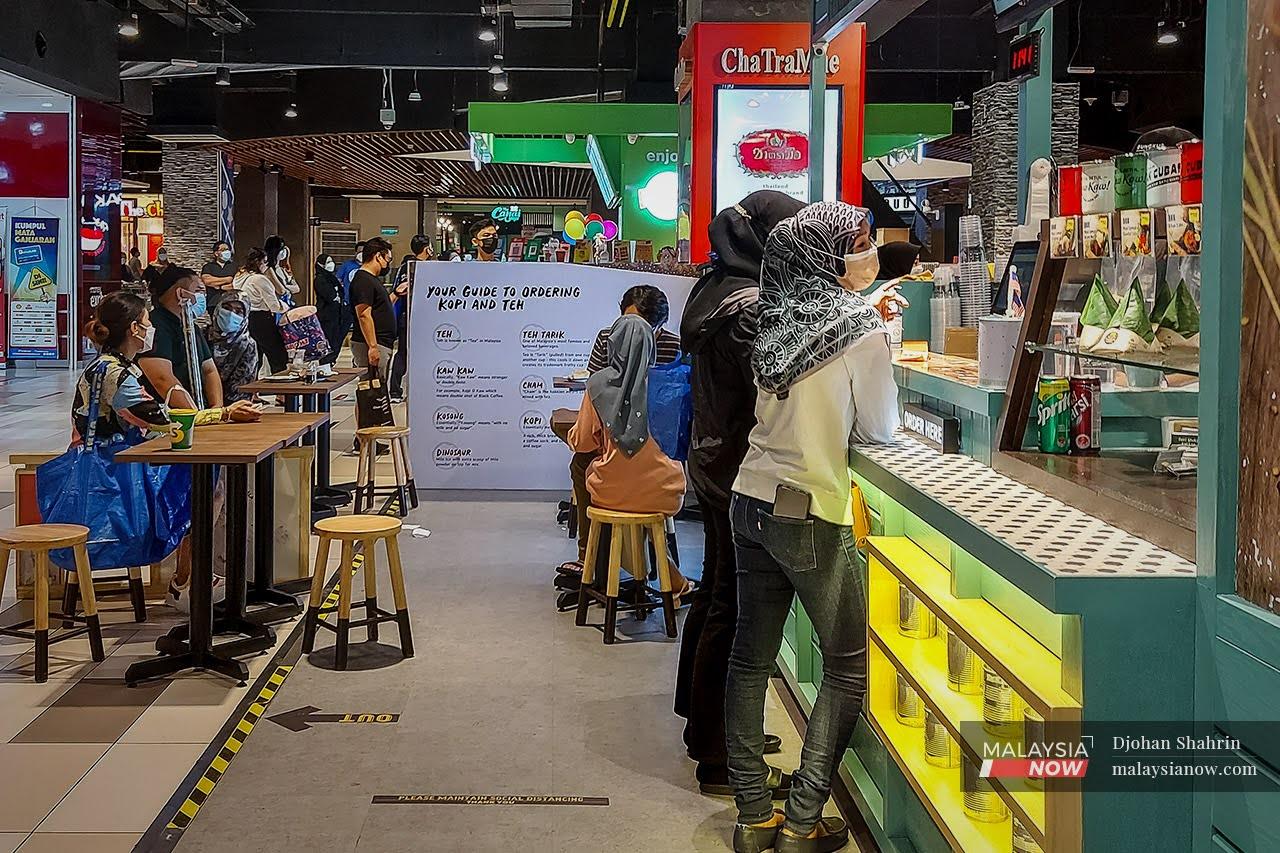 Customers wait for their orders at a food kiosk in a mall in Kuala Lumpur.