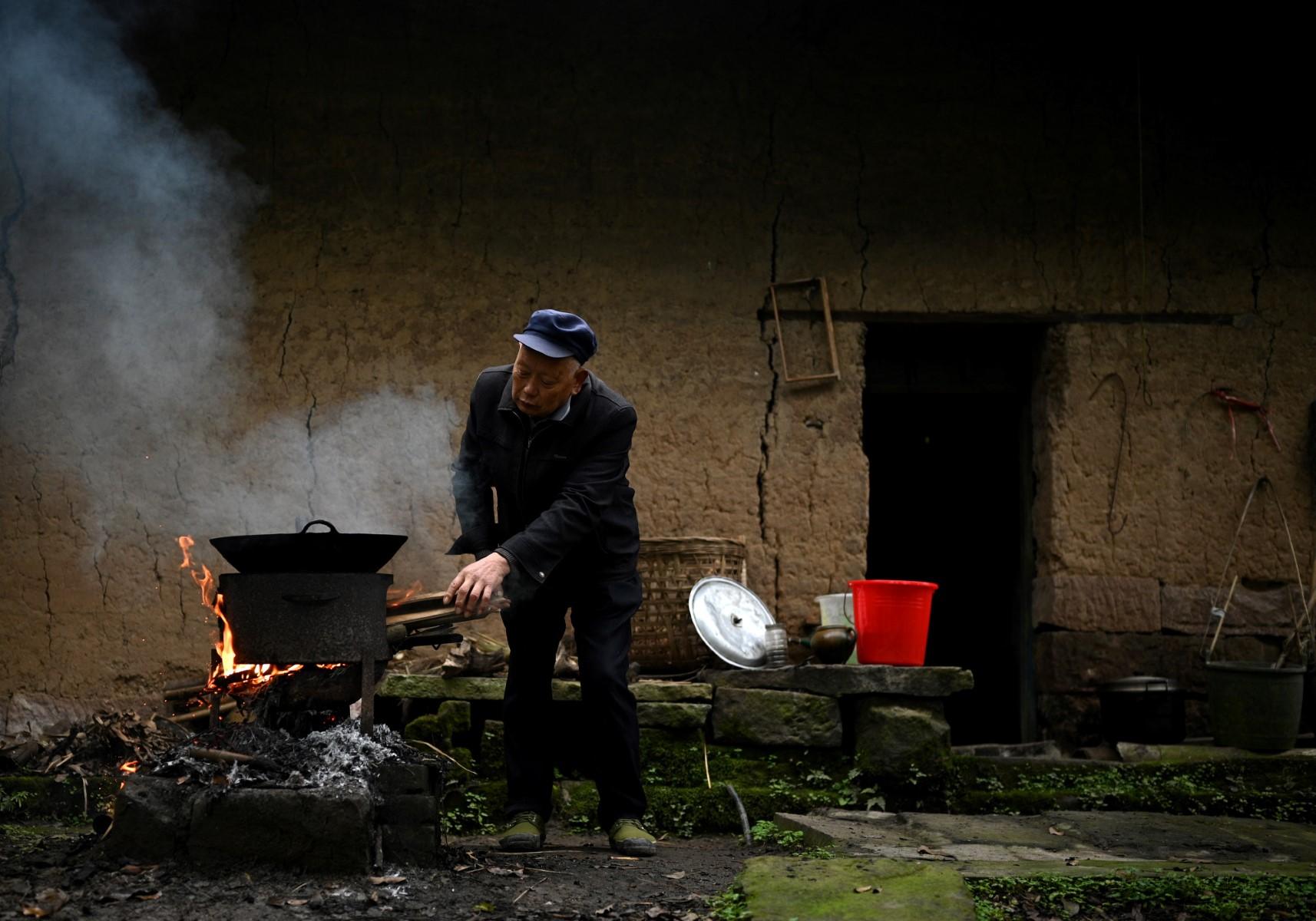 This photo taken on Nov 29, 2020, shows a man cooking a meal in front of his house in Zhongba, a small island near to the southwestern city of Chongqing. Photo: AFP