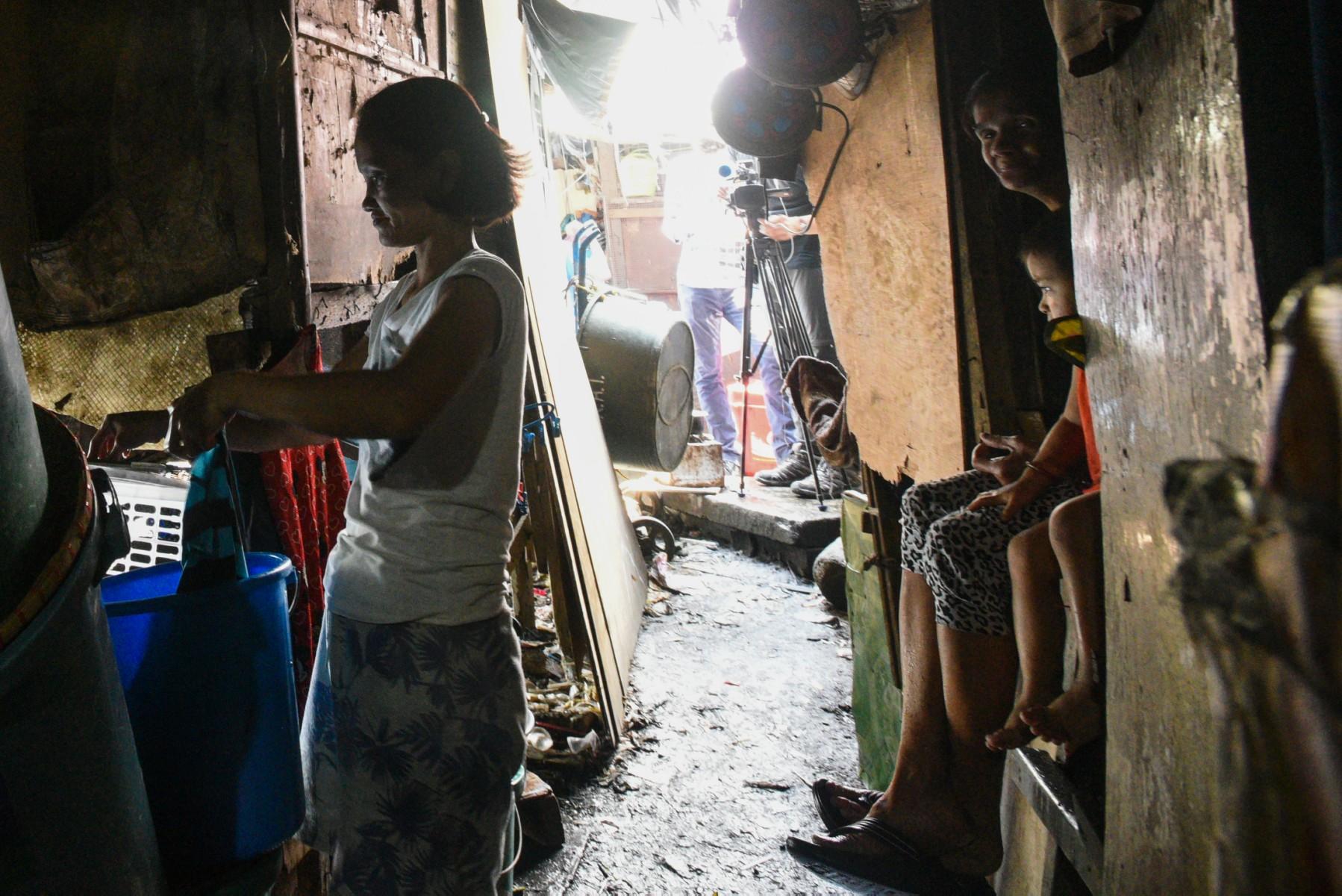 This photo taken on March 18, 2020 shows a mother washing her laundry outside her home along the river in Manila. Photo: AFP