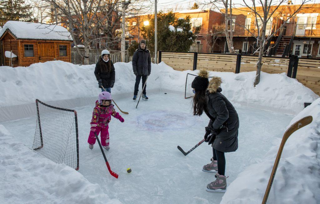 A man and his family play hockey on the ice rink in their backyard in Montreal, Quebec on Feb 10, 2021. Earlier this month Canada broke its previous one-day record for the highest number of people hospitalised with Covid-19, at more than 4,100 nationally. Photo: AFP