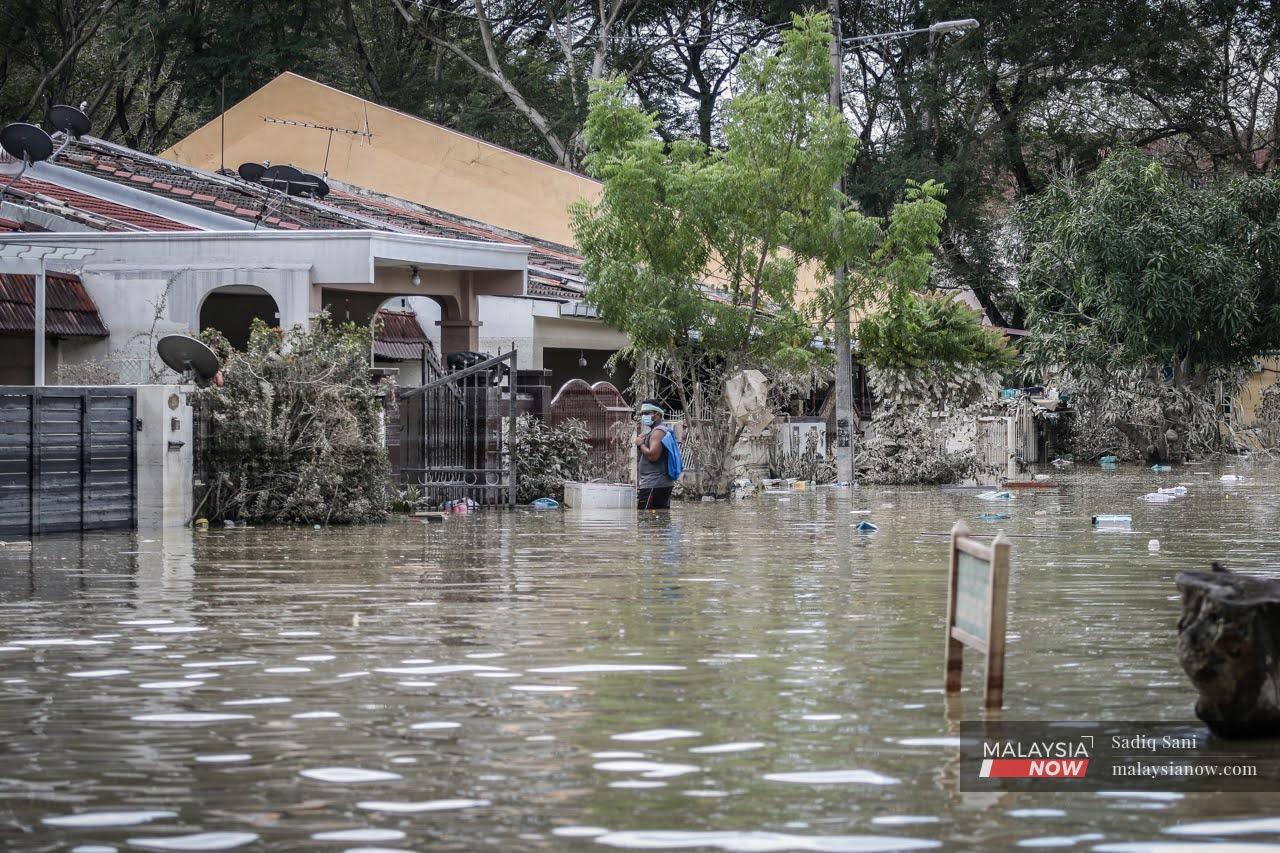 A man stands in knee-deep water outside his house in Taman Sri Muda, one of the areas worst affected by the recent floods in Shah Alam.