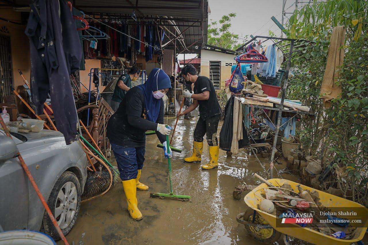 Volunteers help clean the mud from a house in Taman Sri Nanding which was badly affected by the huge floods that hit Hulu Langat.