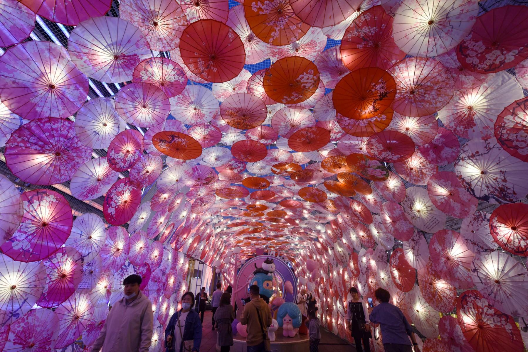 This photo taken on Feb 22, 2021 shows people walking past a display of umbrellas decorated with lights for the upcoming Lantern Festival on a commercial street in Hangzhou, in eastern China's Zhejiang province. Photo: AFP