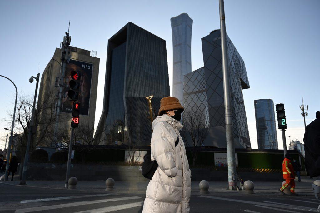 A woman crosses a road in the central business district in Beijing on Dec 16, 2021. Photo: AFP