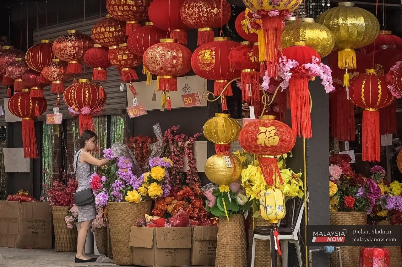 A customer chooses artificial flowers at a shop selling Chinese New Year decorations in Jalan Panggung, Kuala Lumpur.