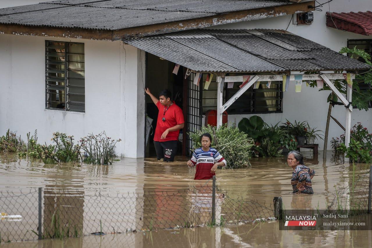 Members of a household stand waist-deep in floodwater outside their home in Bukit Dukong, Balakong after the massive floods which hit Selangor last month.