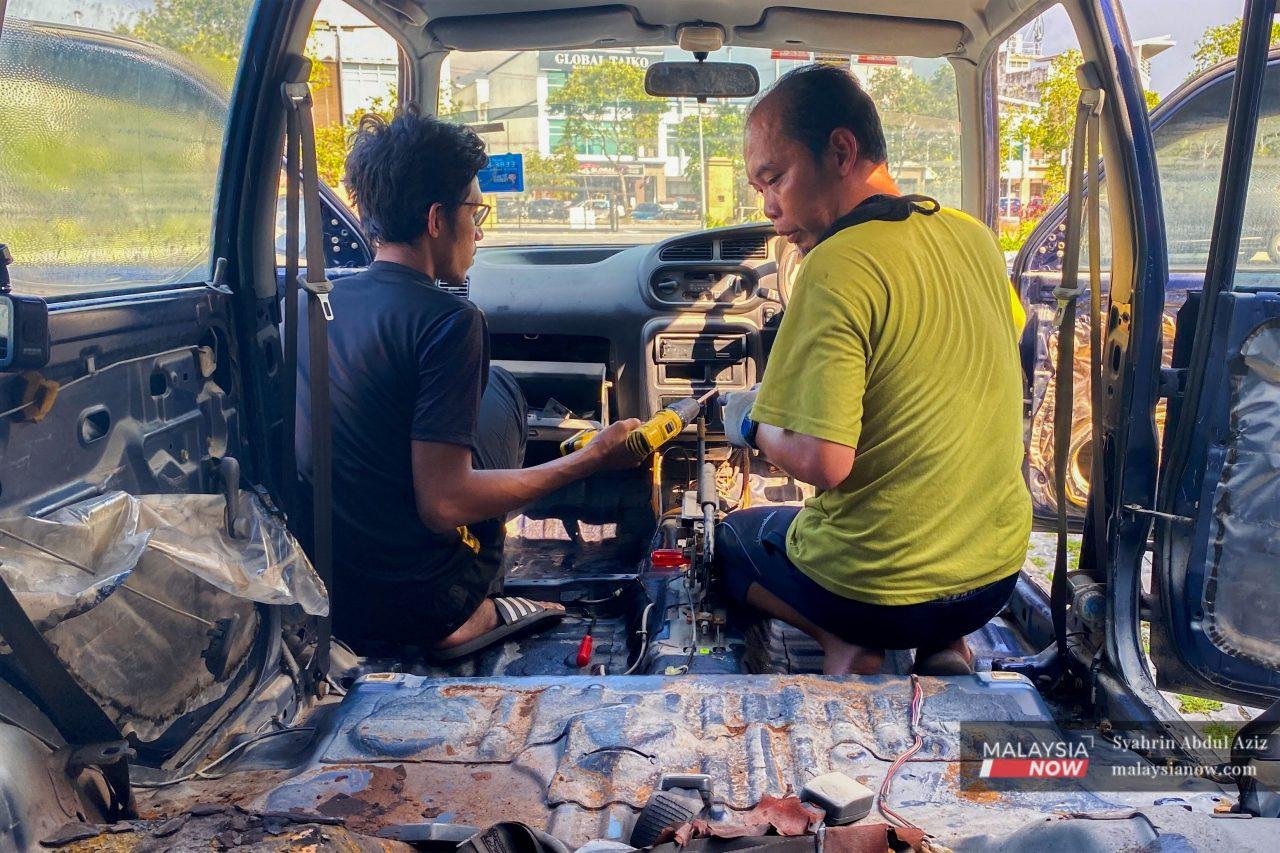 Muhammad Saiful Bahari and Syarul Nizam Wahab work together to clean the interior of a car that was submerged during the recent floods which hit Selangor.