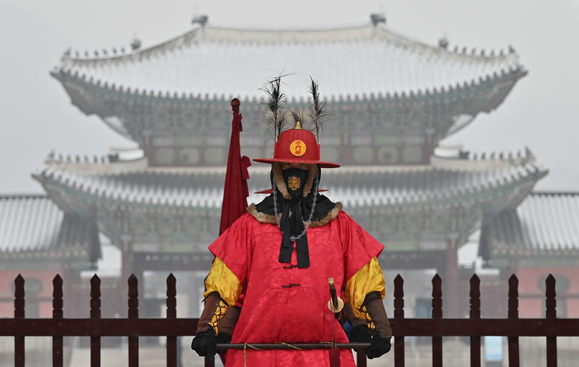 A 'palace guard' stands for tourists in front of the snow-covered Gyeongbokgung Palace in central Seoul on Jan 19. Photo: AFP