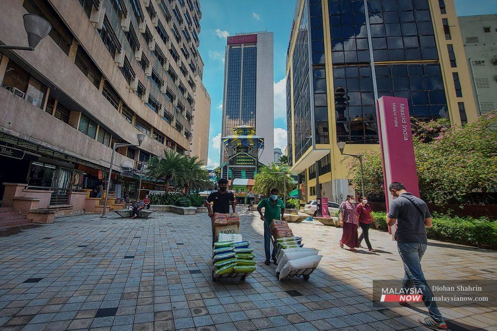 Workers push goods on trolleys in the Jalan Masjid India area in Kuala Lumpur as businesses reopen after months of strict Covid-19 preventive measures. Prime Minister Ismail Sabri Yaakob maintains that the government will not impose another round of movement control order to prevent the spread of Covid-19.