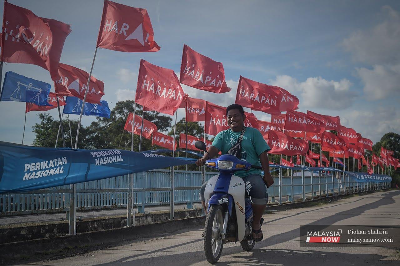 Sebuah motosikal melalui deretan perang bendera antara Perikatan Nasional, Barisan Nasional dan Pakatan Harapan di Bukit Rambai pada PRN Melaka November tahun lalu.