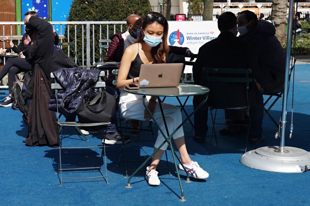A woman wearing a protective mask uses a laptop computer in Bryant Park on March 23, 2021 in New York City. The requirements in New York state, home to around 20 million people, include wearing masks in schools, on public transit and other public indoor spaces. Photo: AFP
