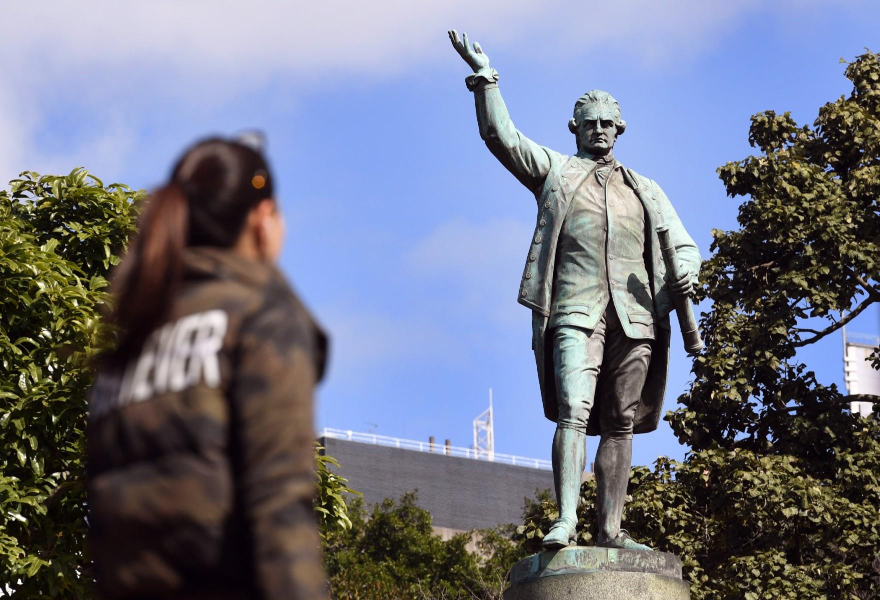 People walk past a statue of Captain James Cook stands in Sydney's Hyde Park on Aug 25, 2017. Photo: AFP