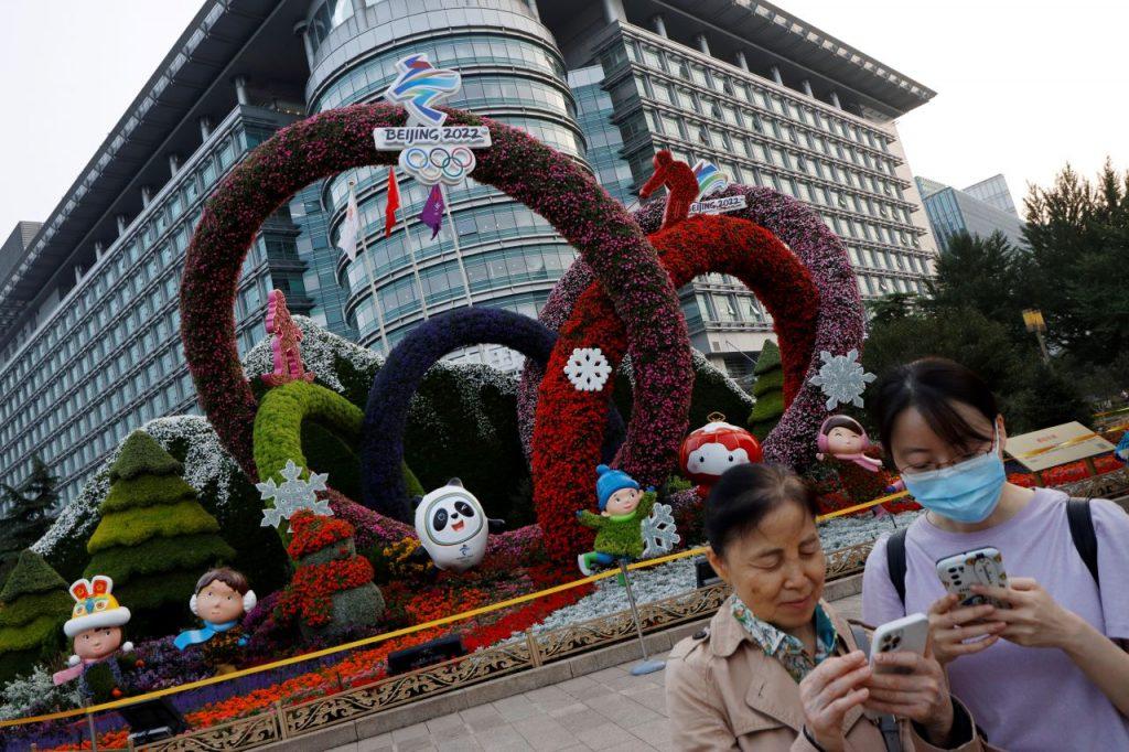 People check their phones near a Beijing 2022 Winter Olympics-themed floral installation set up ahead of the Chinese National Day, in Beijing, China, Sept 30, 2021. Photo: Reuters
