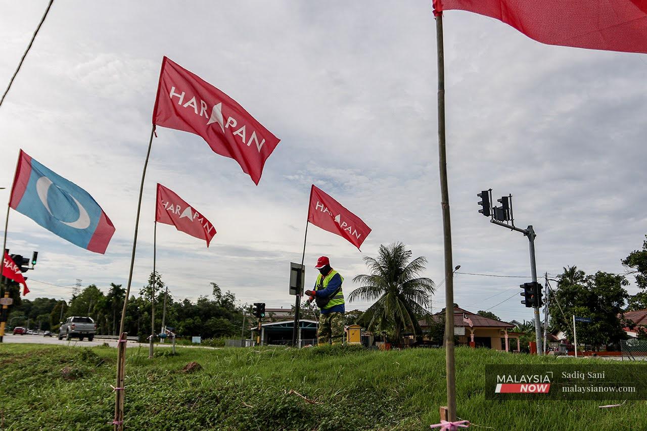 A volunteer puts up Pakatan Harapan and PKR flags along a road in Melaka ahead of the polls which were held last November, and which saw PKR wiped out in the state.