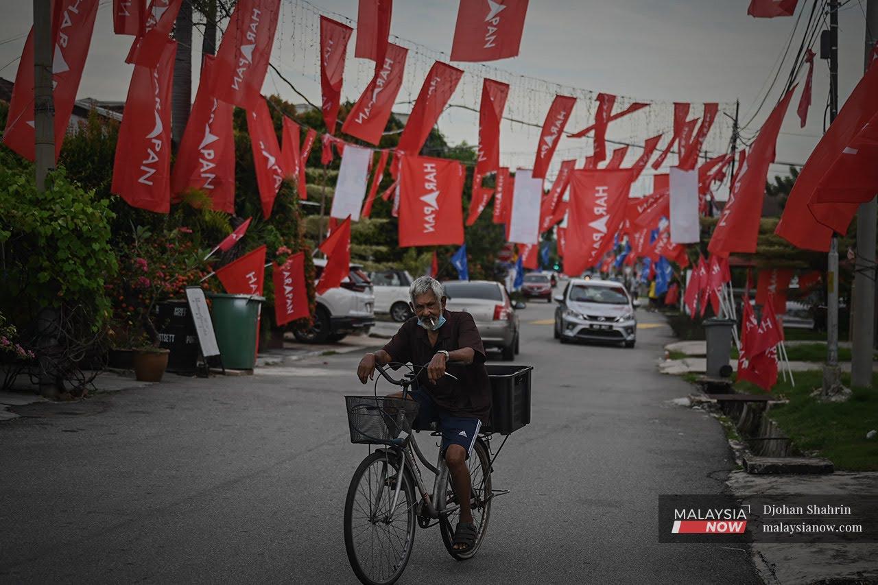 A man rides his bicycle under strings of Pakatan Harapan flags, put up at the Portuguese Settlement in Melaka ahead of the state election last November.