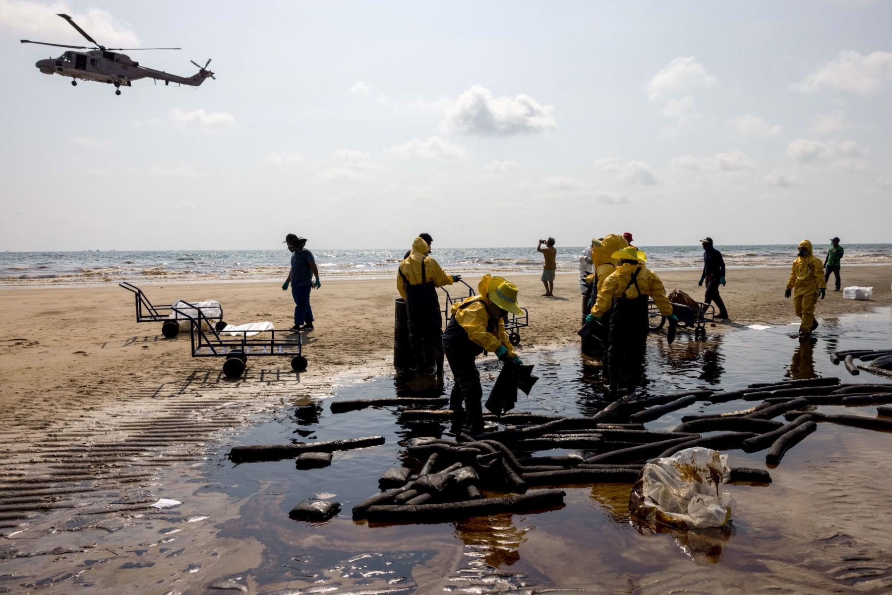 A helicopter flies overhead as workers clean up crude oil on Mae Ram Phueng beach following a spill caused by a leak in an undersea pipeline owned by Star Petroleum Refining Public Company Limited in Rayong on Jan 29. Photo: AFP