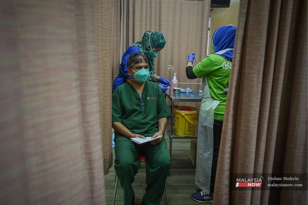 A health worker prepares a syringe of Pfizer vaccine to administer as a booster shot to a doctor at KPJ Tawakkal in Jalan Pahang, Kuala Lumpur.