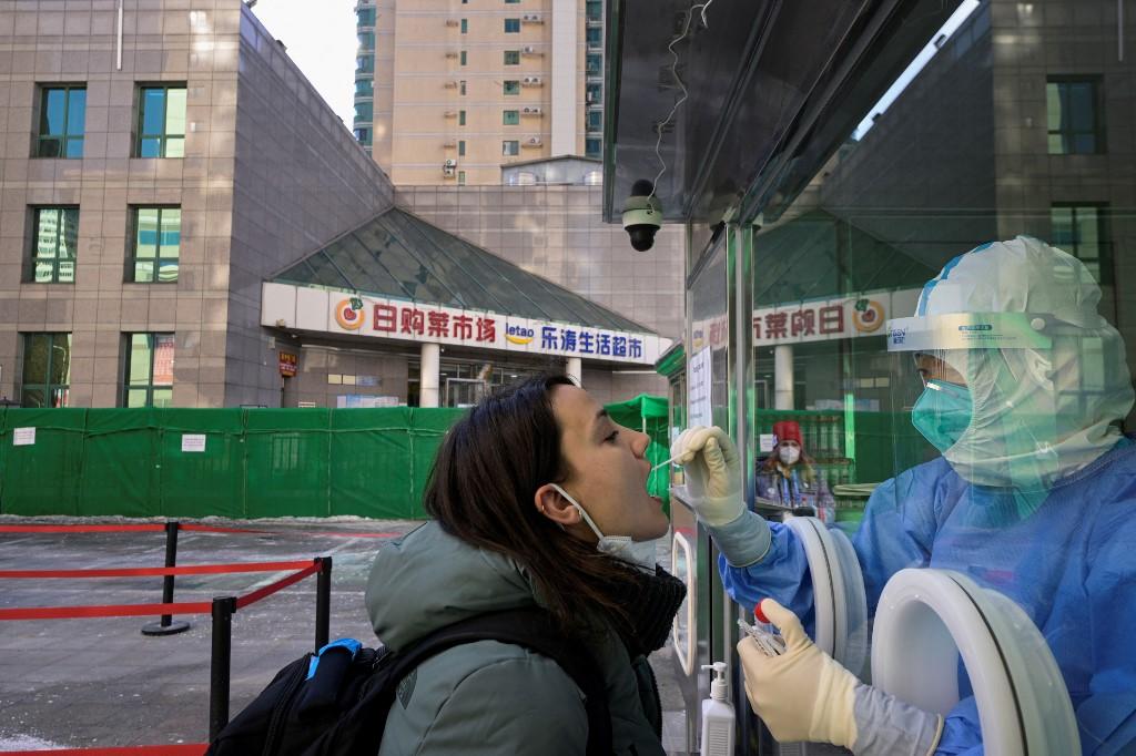A health worker collects a swab sample from a journalist to test for Covid-19 at the parking lot of a hotel in Beijing on Feb 2, ahead of the Beijing 2022 Winter Olympic Games. Photo: AFP
