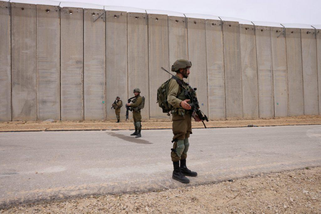 Tentera Israel berkawal di tepi tembok pemisah di sepanjang sempadan Gaza berhampiran Moshav Netiv HaAsara di selatan Israel pada 7 Disember. Gambar: AFP