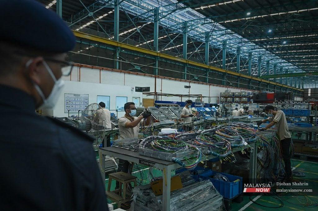 A police officer checks SOP compliance at a factory in Kota Damansara, Selangor, on the first day of the total lockdown imposed on June 1 last year.