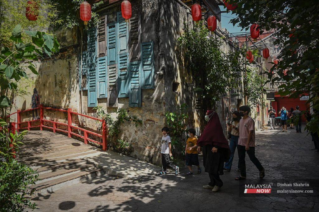 A family explores the Kwai Chai Hong area in Kuala Lumpur, a popular tourist spot decorated with traditional murals by the Chinese community in Jalan Panggung.