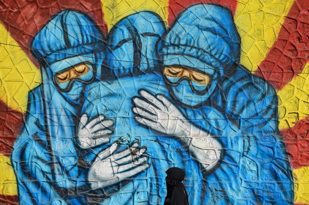 A pedestrian walks past a wall mural depicting health workers wearing personal protective equipment suits to spread awareness about Covid-19 in Mumbai on Jan 29. Photo: AFP