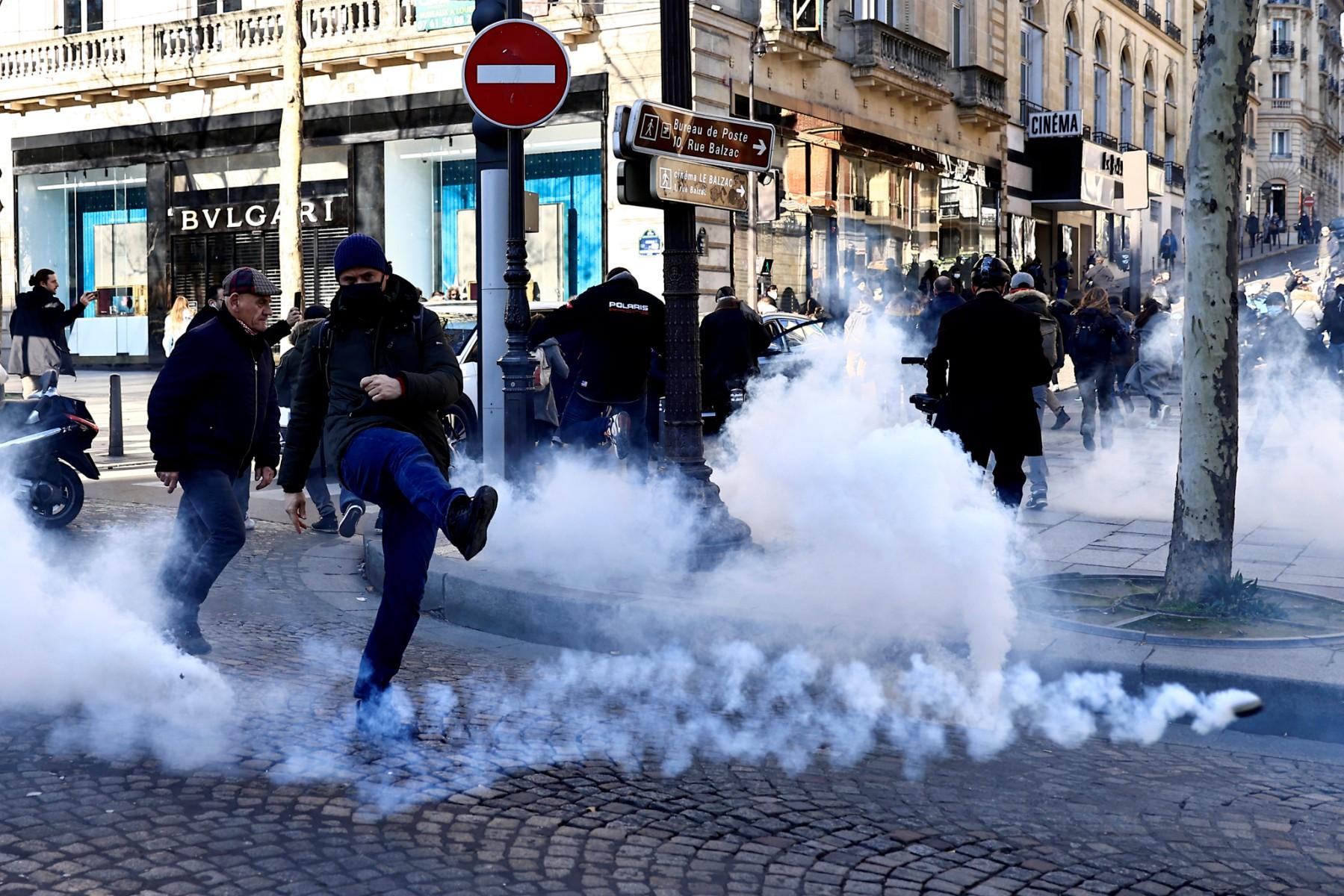 A man kicks a tear gas canister fired by French anti-riot policemen on the Champs Elysees in Paris on Feb 12, as convoys of protesters arrived in the French capital. Photo: AFP