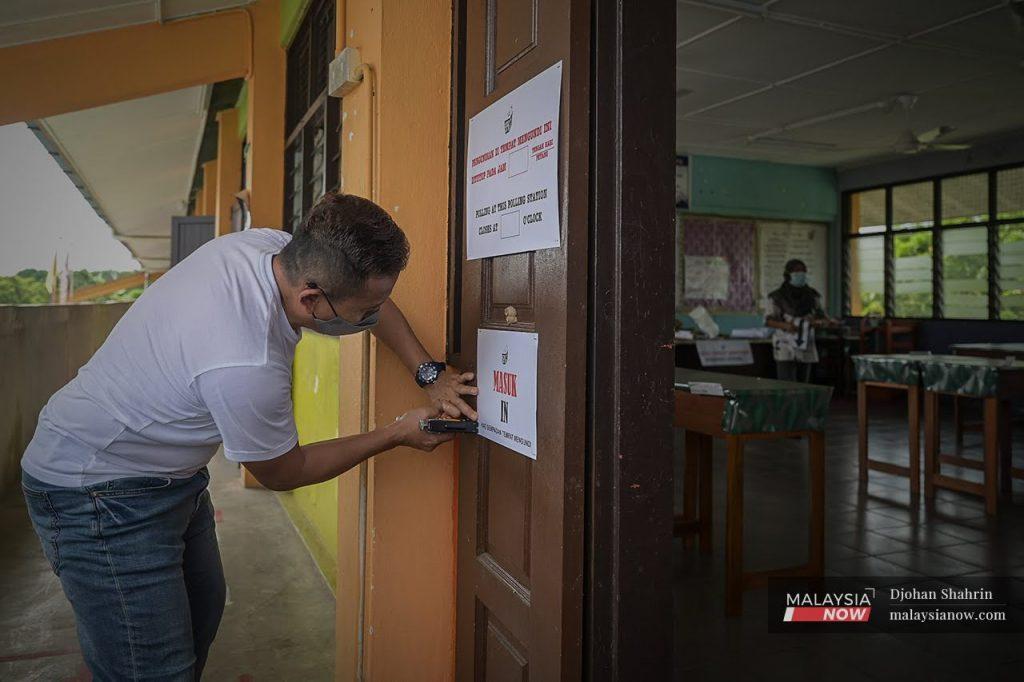 An election worker pastes a sign on the door of a school used as a polling centre in the recent Melaka election.