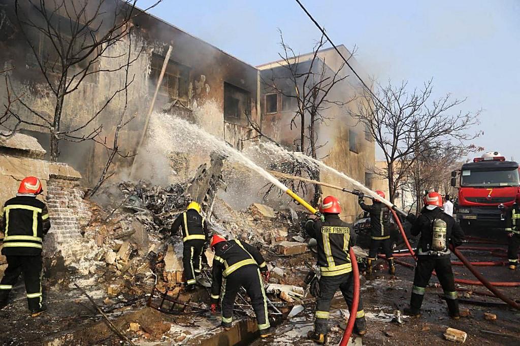 A handout picture provided by the news agency Tasnim on Feb 21 shows firefighters putting out a blaze at the crash site of a fighter jet in a residential area of the northwestern city of Tabriz. Photo: AFP