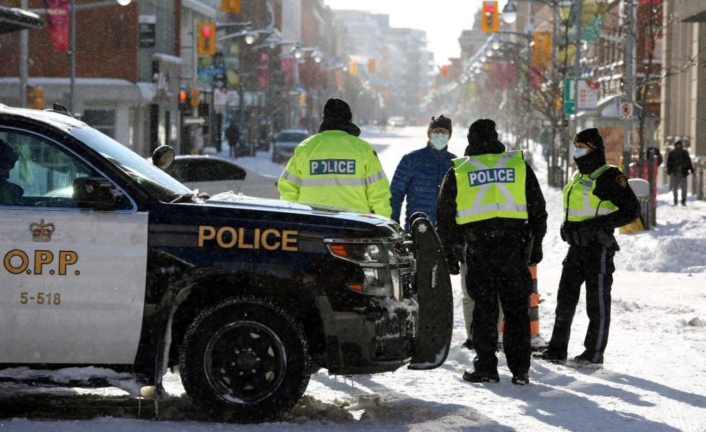 Police officers speak to a pedestrian in downtown Ottawa as non-essential traffic and pedestrians are diverted away from the protesters demanding an end to Covid-19 mandates, on Feb 18. Photo: AFP