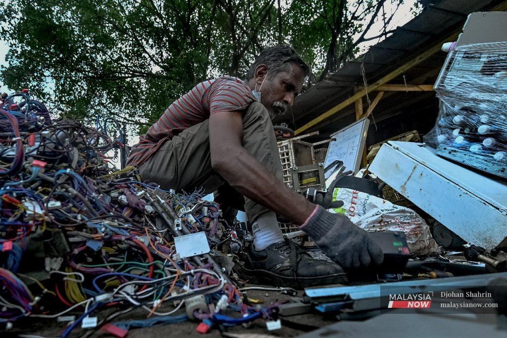 A man spends his days going through piles of waste, separating paper, plastic bottles, cardboard boxes, aluminium tins, and old wires which need to be categorised before being sold to third parties for recycling.