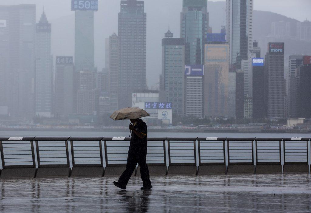 A man walks in the rain along Victoria Harbour in the Kowloon district of Hong Kong on Aug 16, 2021. Photo: AFP