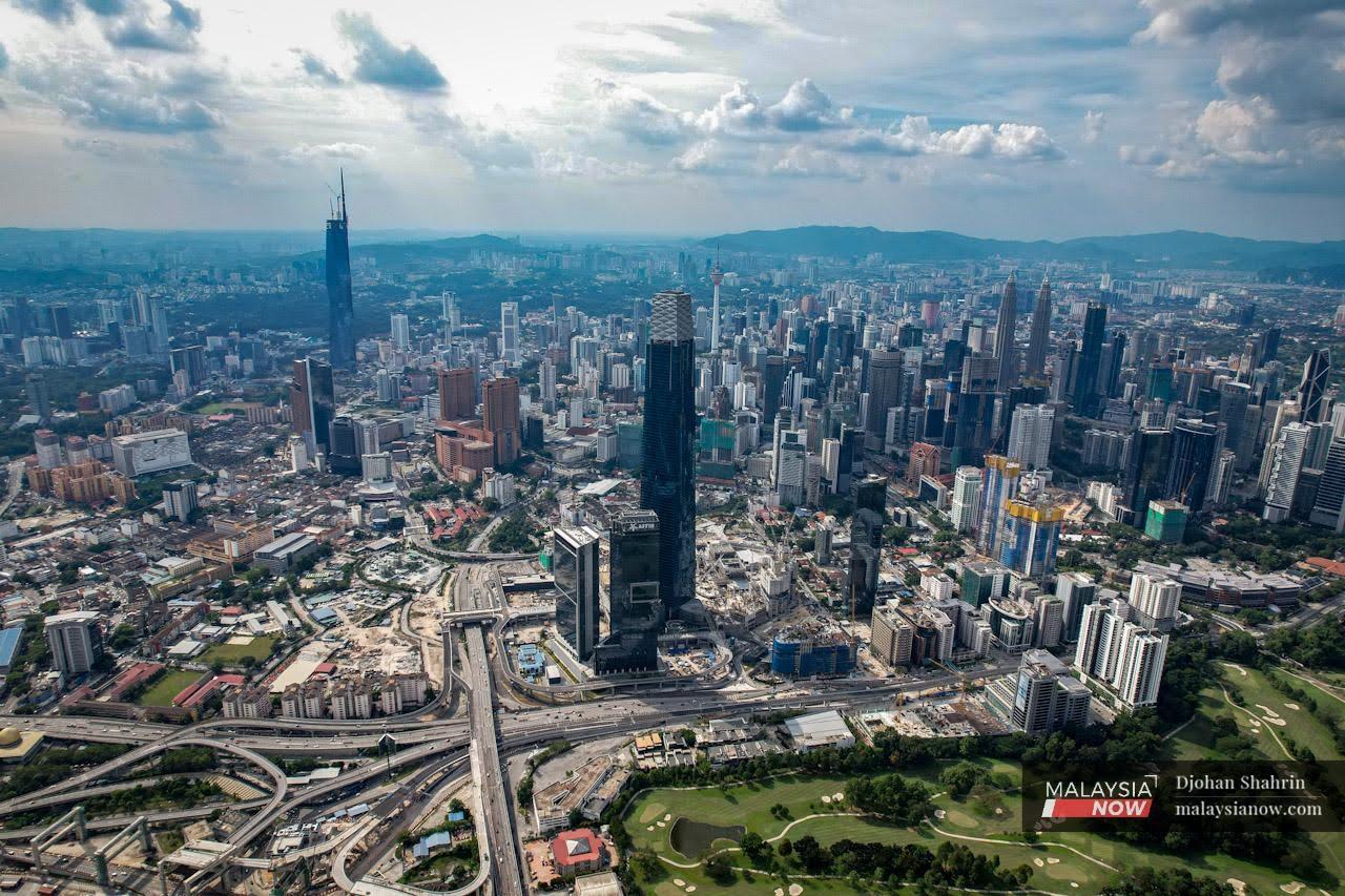 An aerial view of Kuala Lumpur, including the Tun Razak Exchange Tower and the iconic Petronas Twin Towers and KL Tower.