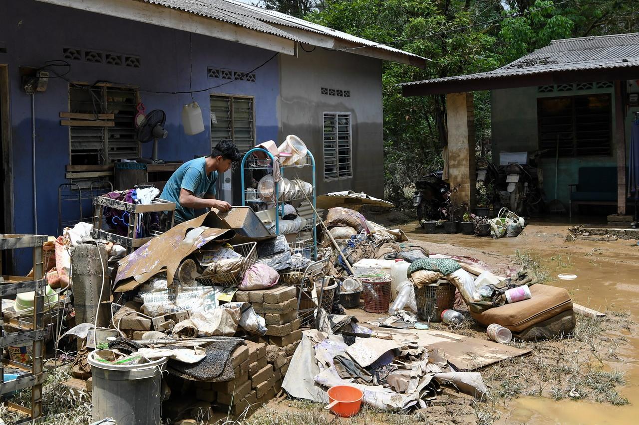 A teenager sorts through household items to be cleaned or thrown away at his home in Kampung Chemuak in Dungun, Terengganu. Photo: Bernama