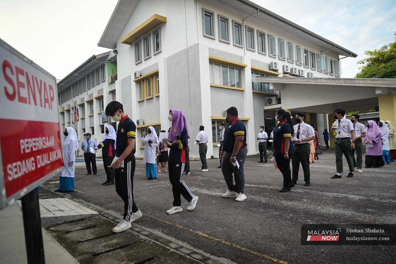 Students queue to enter the exam hall at a school in Kuala Lumpur today, as the 2021 SPM examination begins.