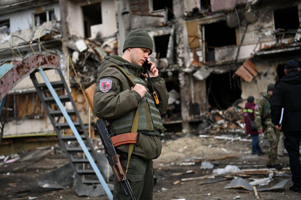 A Ukrainian serviceman talks on a smartphone in front of a damaged residential building at Koshytsa Street, a suburb of the Ukrainian capital Kyiv, where a military shell is said to have hit, on Feb 25. Photo: AFP