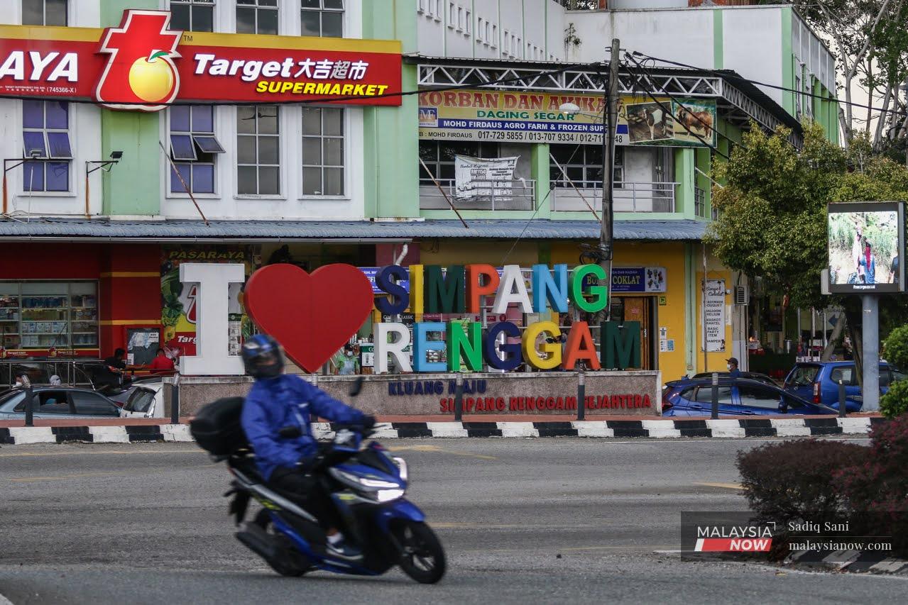 A motorcyclist rides past a sign reading 'I love Simpang Renggam' in the middle of Simpang Renggam town, ahead of the Johor state election on March 12.