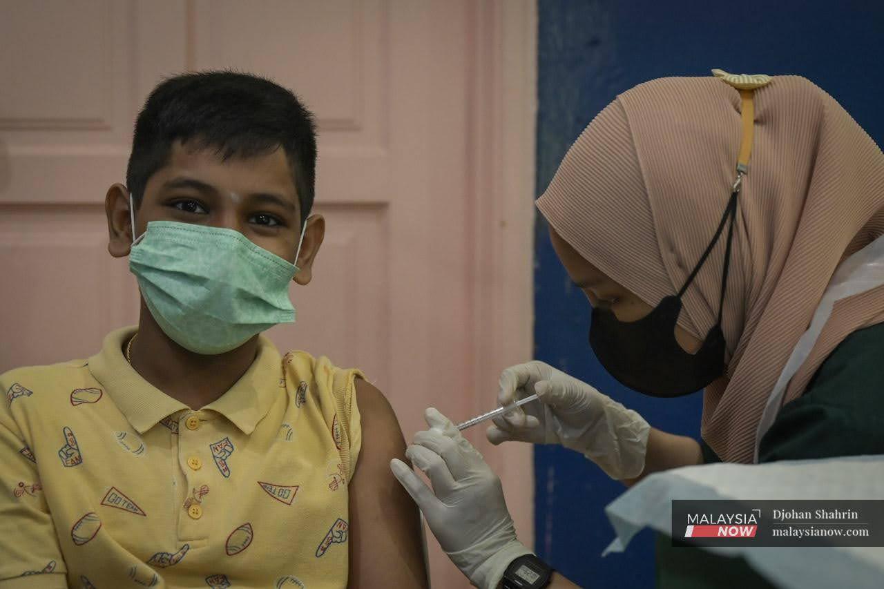 A young boy waits as a nurse administers a dose of Covid-19 vaccine for children at the Dewan Komuniti Taman Bukit Mewah vaccination centre in Kajang.