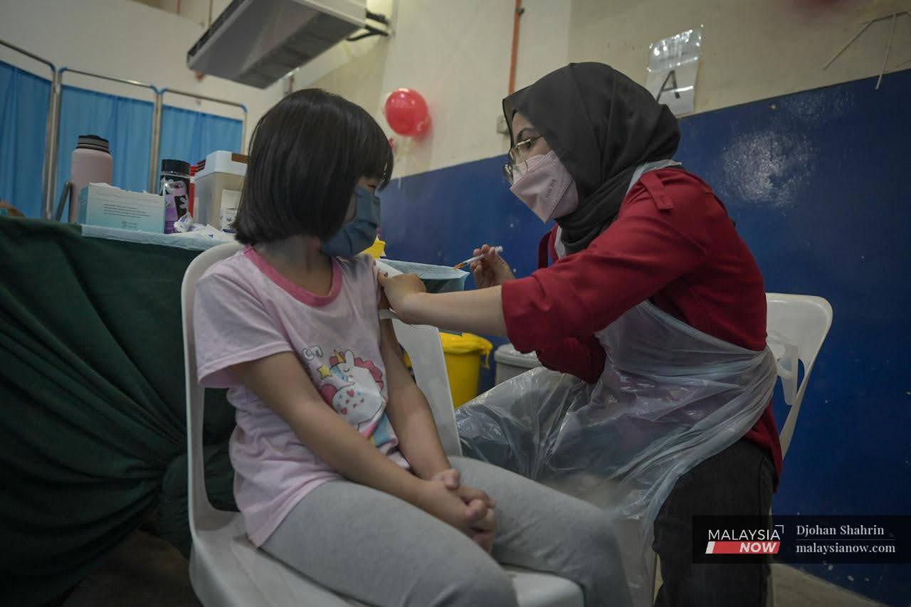 Petugas kesihatan dari Megaklinik Zahran memberi suntikan vaksin kepada kanak-kanak pada Program Imunisasi Covid-19 Kanak-Kanak (PICKids) 5 hingga 11 tahun di PPV Dewan Komuniti Taman Bukit Mewah, Kajang.