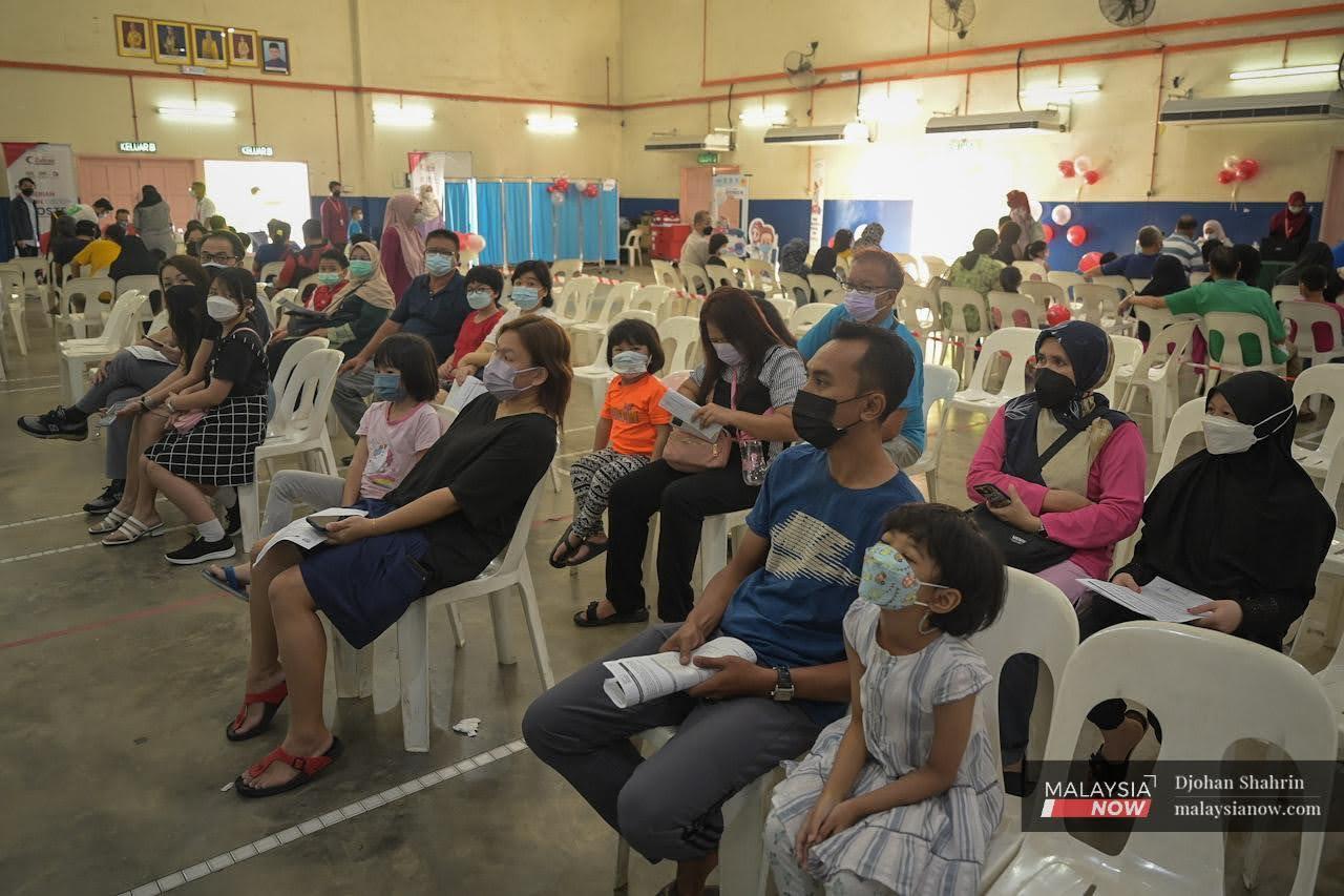 Parents and guardians wait with their children at the Dewan Komuniti Taman Bukit Mewah vaccination centre in Kajang.