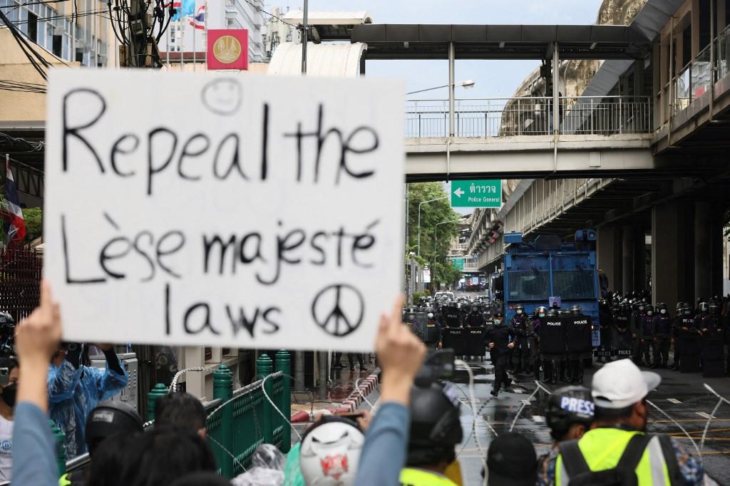 A protester holds up a sign calling for the reform of the monarchy laws as they face off with police in riot gear during an anti-government demonstration in Bangkok on Sept 4, 2021. Thailand has some of the world's strictest lese majeste laws, which carry punishments of three to 15 years in jail for each offence. Photo: AFP