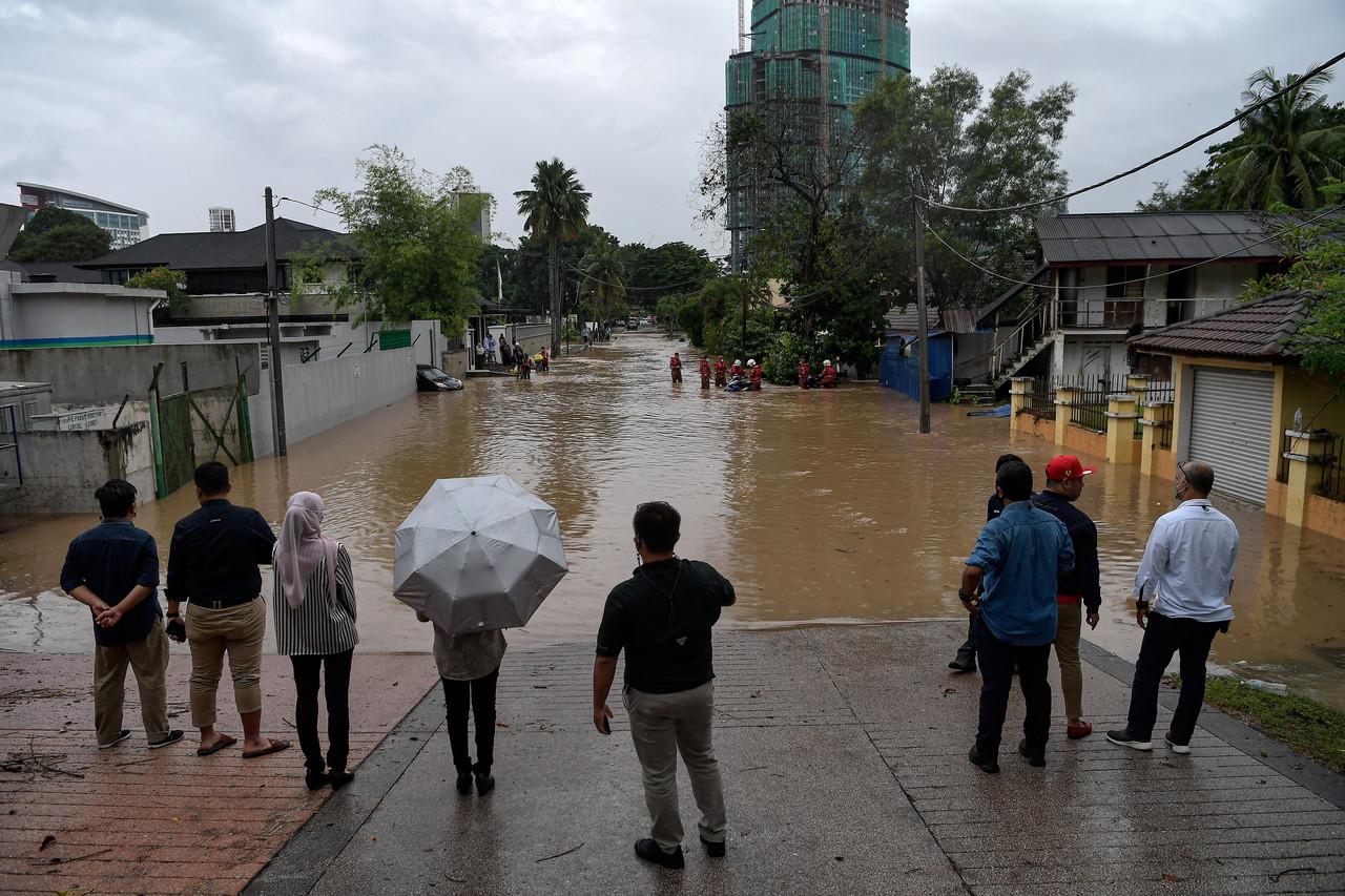 Orang ramai dilihat terkandas kawasan air bertakung akibat hujan lebat di sekitar kawasan perumahan di Lorong Gurney, Kuala Lumpur. Gambar: Bernama