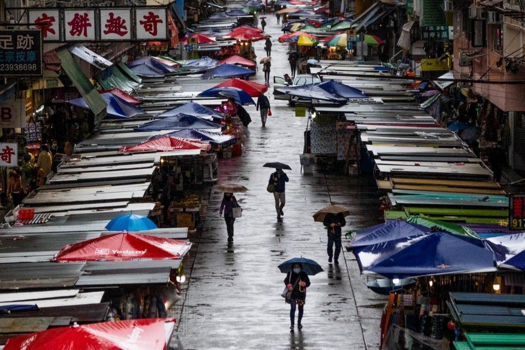 Pedestrians walk in the rain in Hong Kong’s Mongkok area on Feb 20. Most of the Chinese-ruled city's more than 2,200 deaths have been in the past two weeks. Photo: AFP