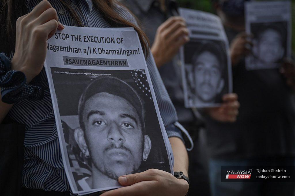 Activists hold up posters showing the face of Nagaenthran K Dharmalingam, a Malaysian on death row in Singapore whose case garnered international attention.