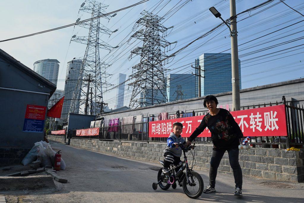 A woman guides a boy learning to cycle below power lines in Beijing on Oct 13, 2021. As of March 9, mainland China had reported 112,385 cases with confirmed symptoms, including local ones and those arriving from outside mainland. Photo: AFP