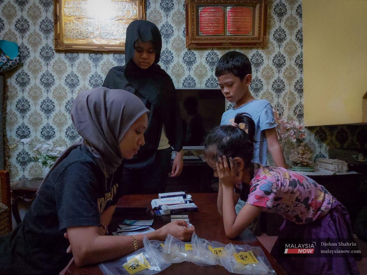 A woman waits with her children to see the results of their Covid-19 self-tests.